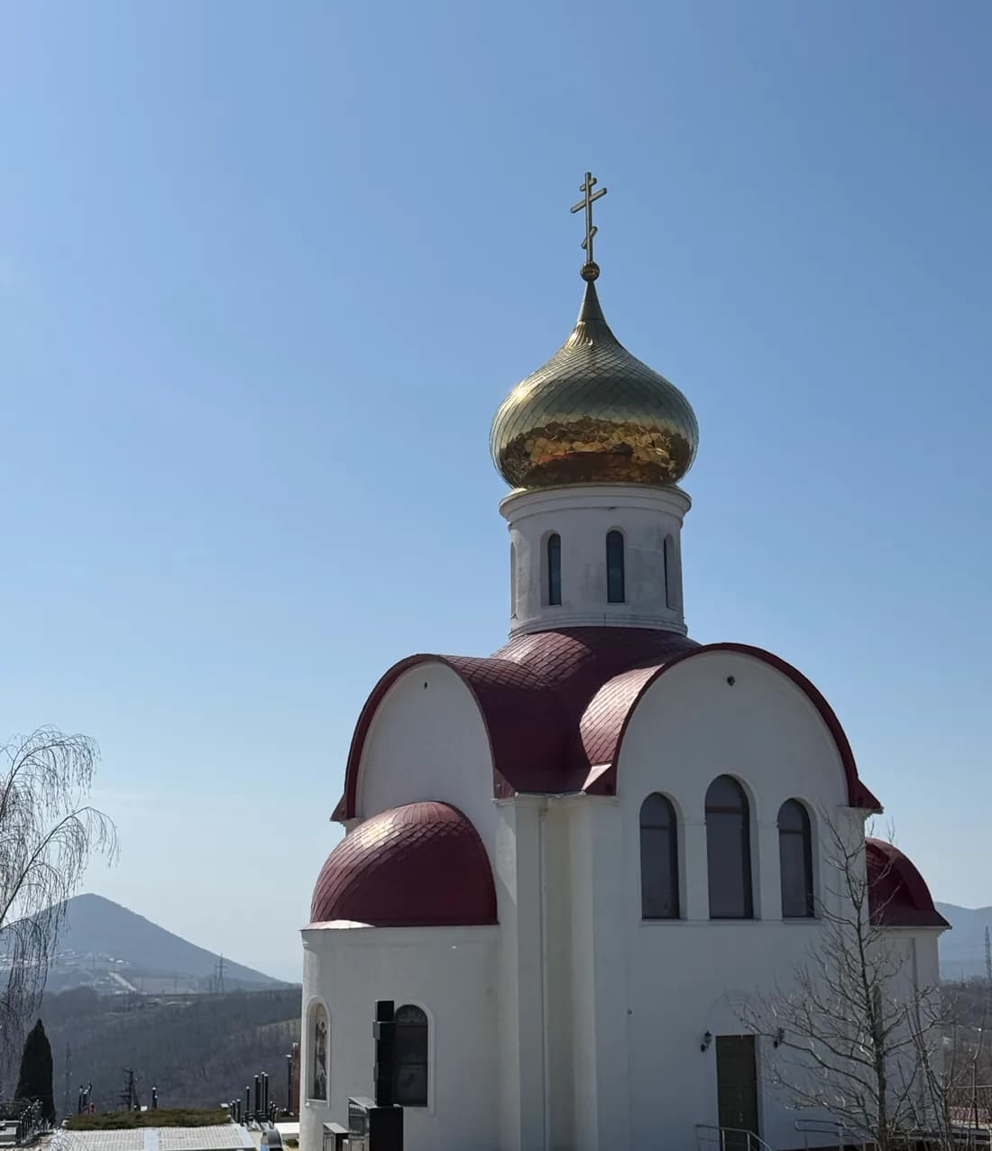 Храм святых Жён-Мироносиц: белый фасад с бордовой кровлей и золотым куполом
