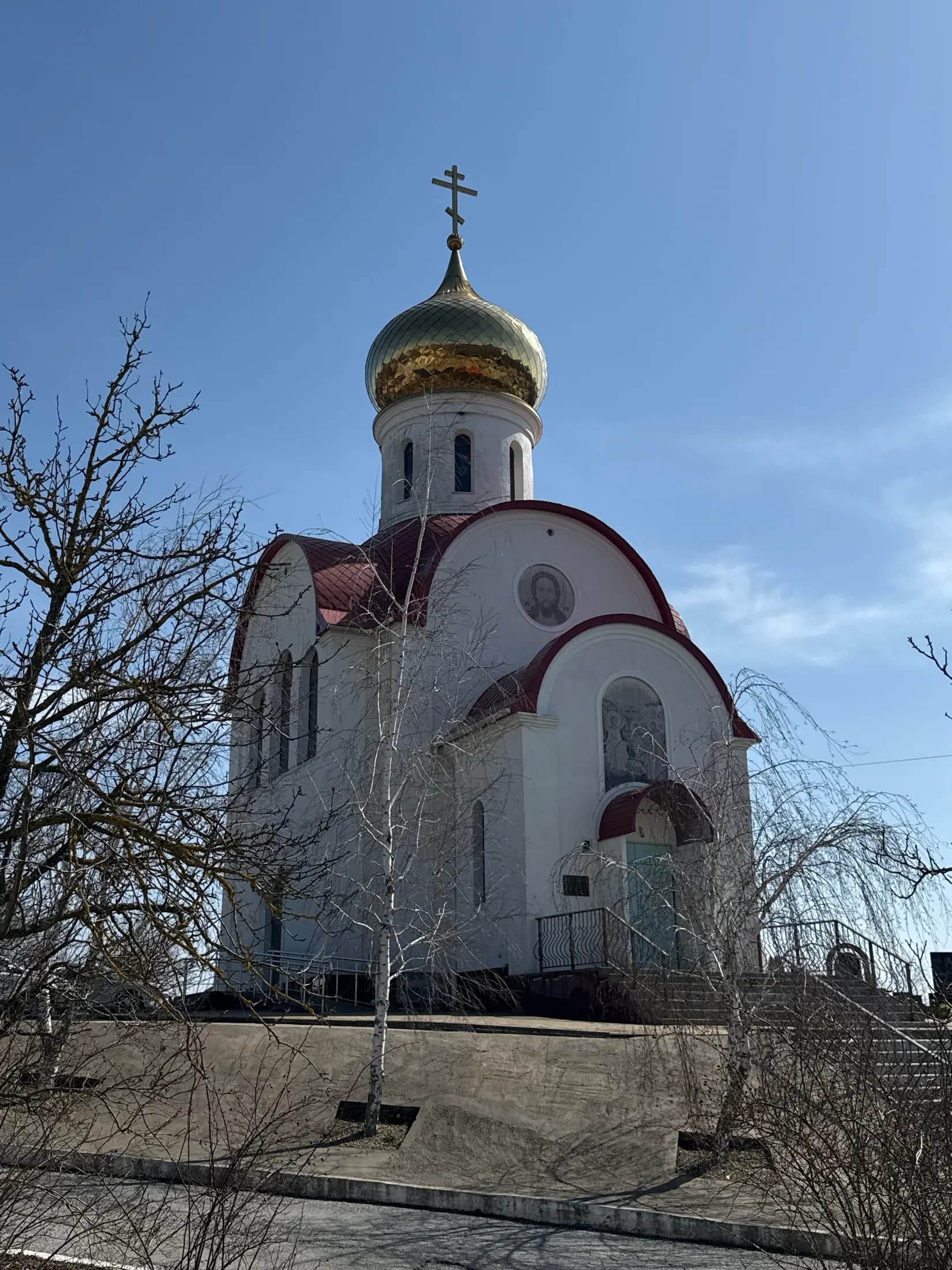 Храм святых Жён-Мироносиц в Новороссийске: белый фасад, красная кровля и золотой купол на фоне неба